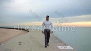 男跑者正沿着美丽的海滨散步，一边用耳机听音乐。 准备好锻炼了。